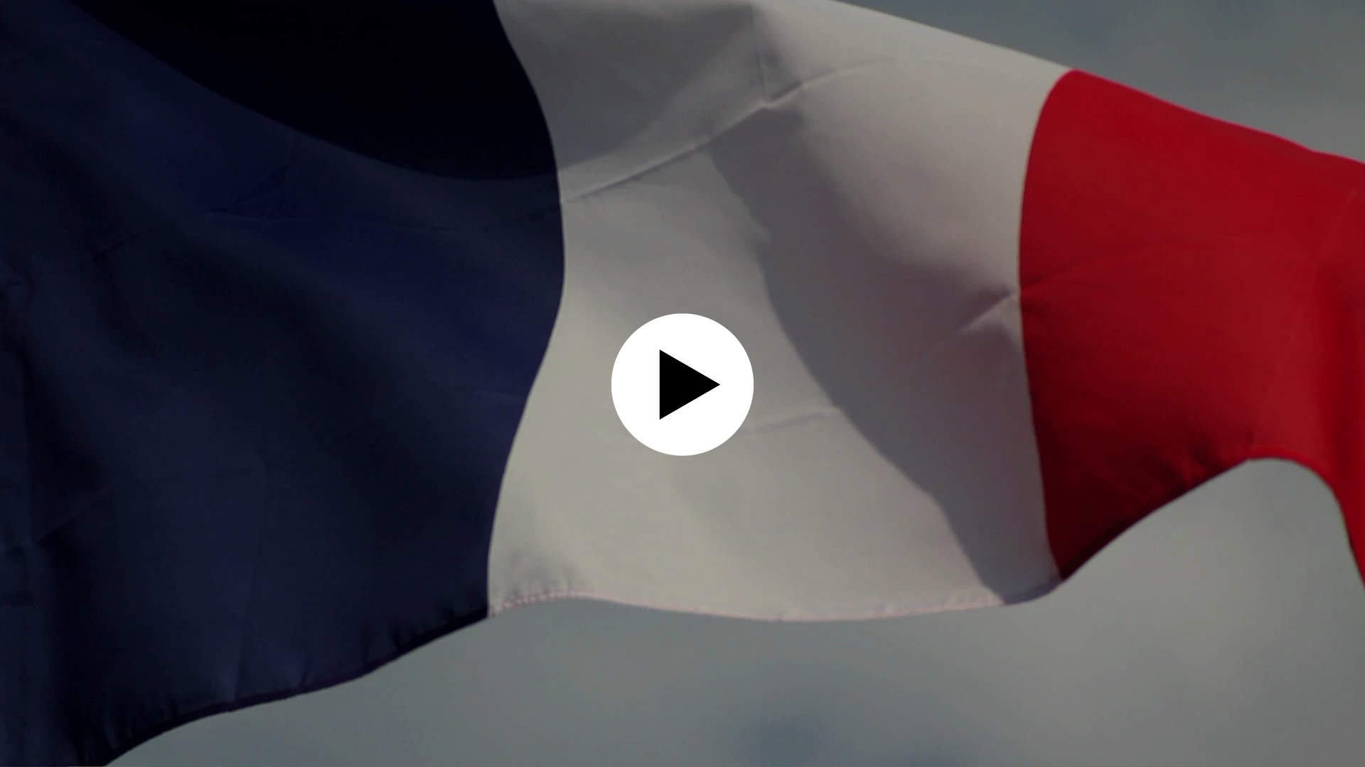 Image du draperau français flottant au vent. Icône play en surimpression indiquant que l'image est cliquable et mène vers un contenu vidéo.