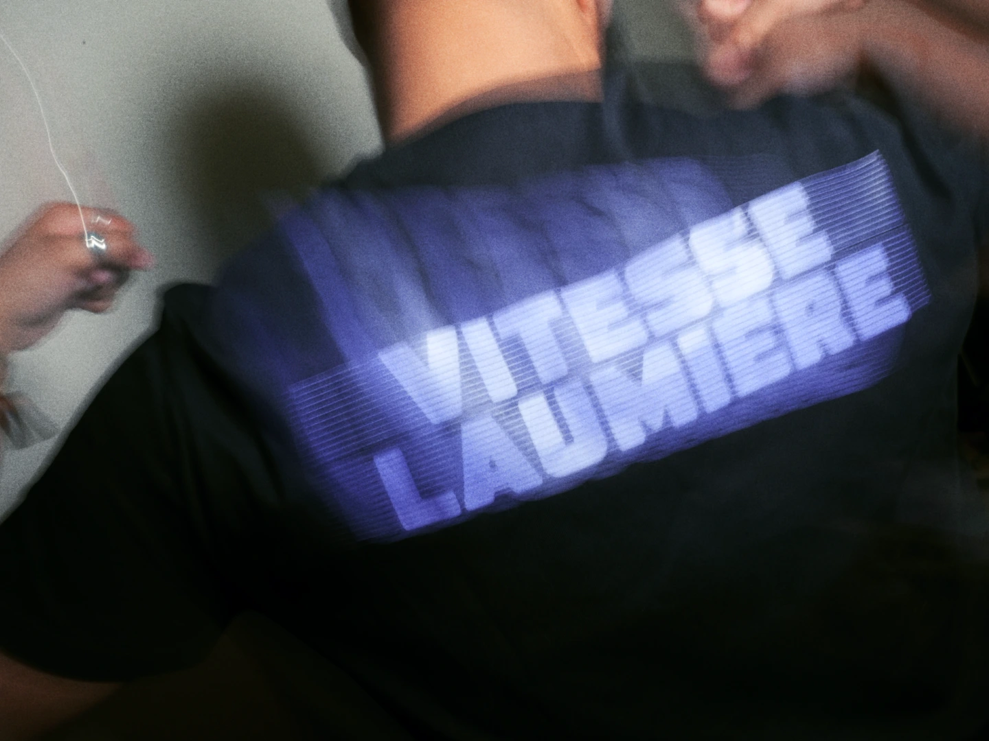 Le logotype de Vitesse Laumière en couleur sur un fond abstrait en nuances de gris.